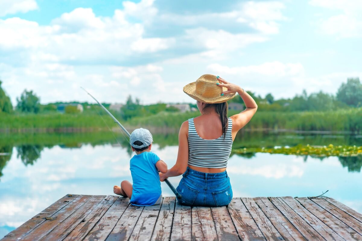 "बच्चों के साथ झील के किनारे मछली पकड़ने का आनंद लेता एक परिवार।"
